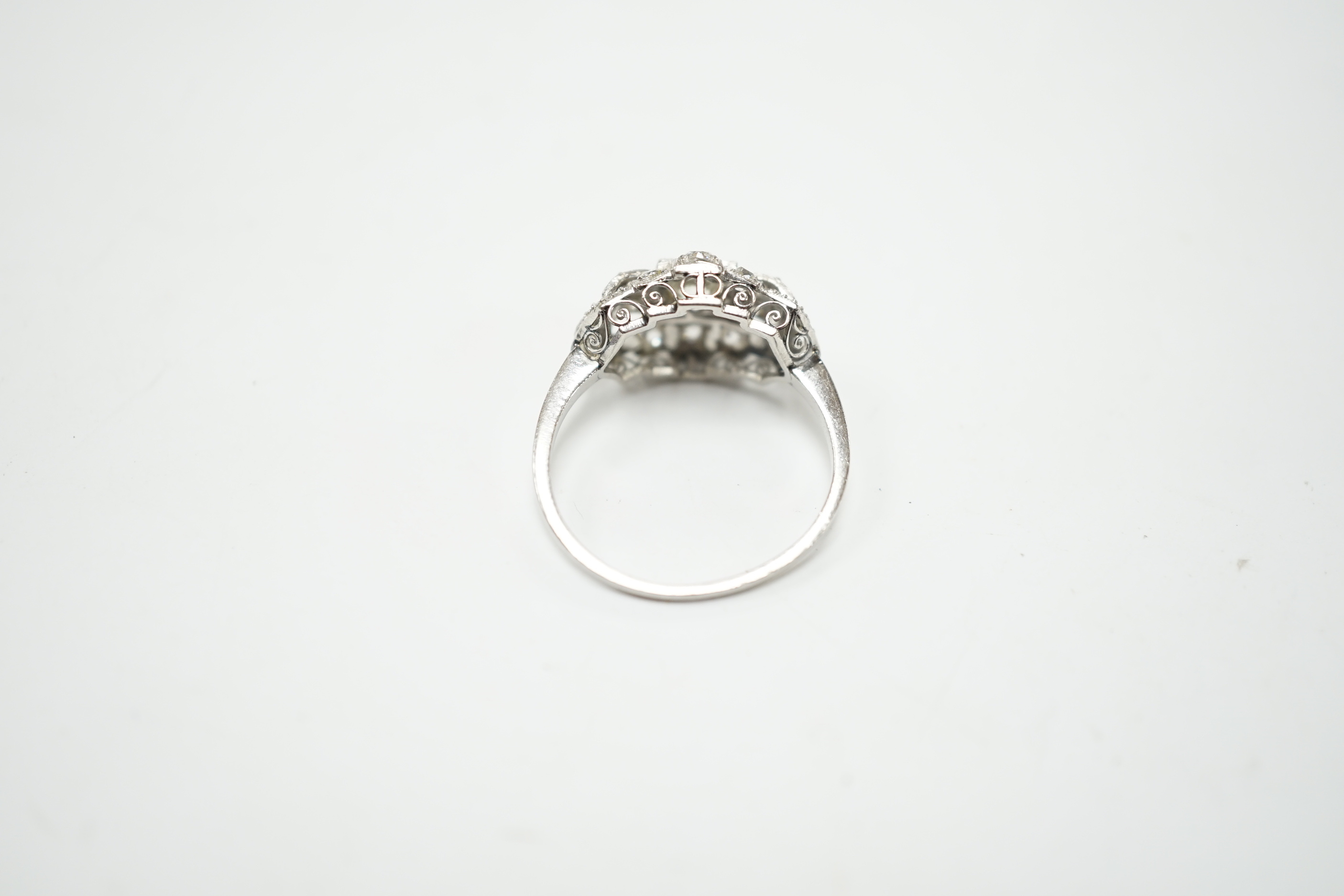 An Art Deco style white metal and millegrain set diamond cluster ring, size N/O, gross weight 4.1 grams, the central stone with a diameter of approximately 4.5mm.
